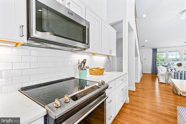 kitchen featuring white cabinetry, backsplash, light hardwood / wood-style flooring, and stainless steel appliances