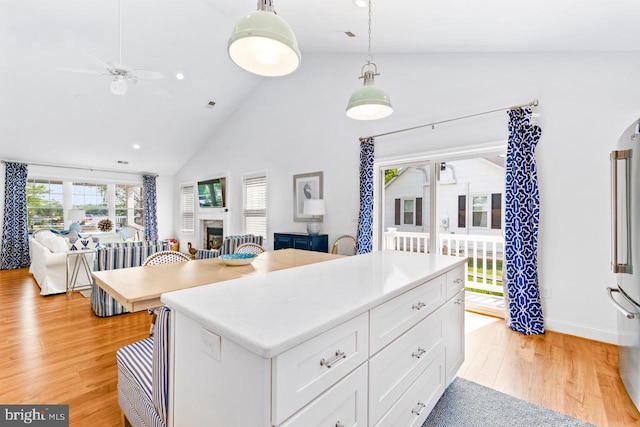 kitchen with white cabinetry, hanging light fixtures, a wealth of natural light, and light hardwood / wood-style flooring