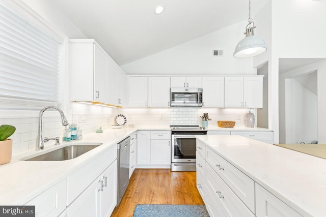 kitchen featuring sink, white cabinetry, vaulted ceiling, pendant lighting, and stainless steel appliances