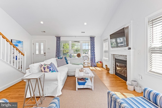 living room featuring lofted ceiling, a high end fireplace, and light wood-type flooring