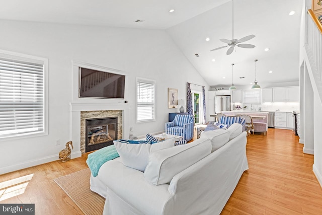 living room featuring ceiling fan, high vaulted ceiling, and light hardwood / wood-style flooring