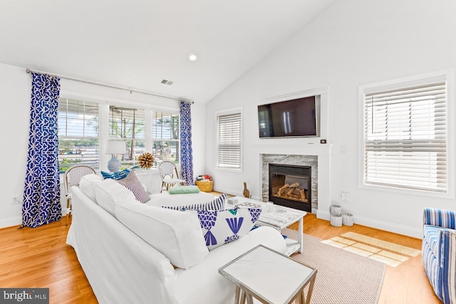 living room featuring vaulted ceiling, light hardwood / wood-style floors, and a premium fireplace