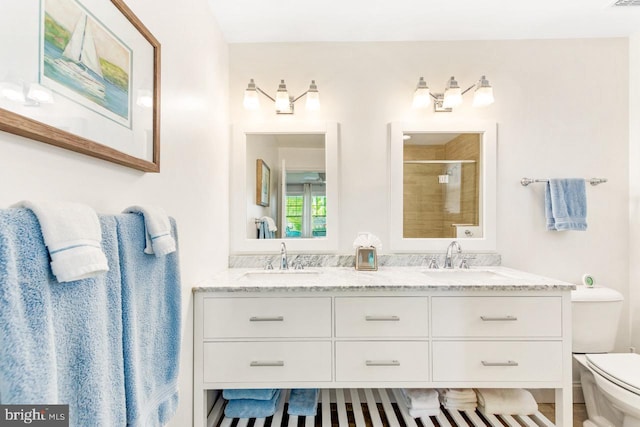 bathroom featuring vanity, a shower with door, and toilet