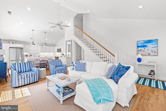 living room featuring ceiling fan, high vaulted ceiling, and light wood-type flooring