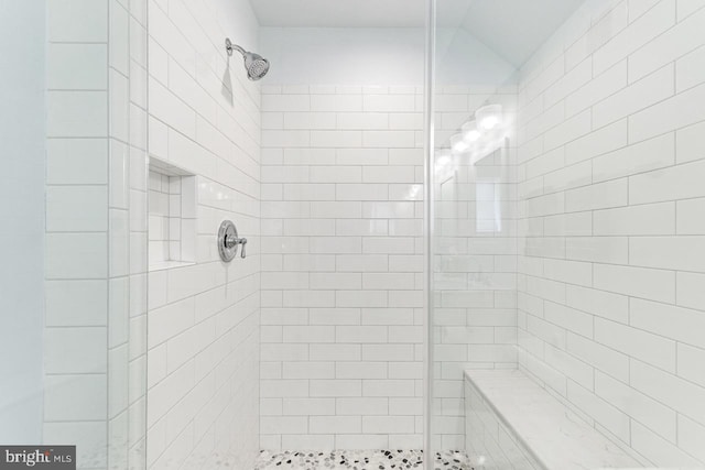 bathroom with tiled shower and vaulted ceiling