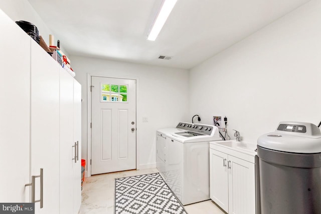 clothes washing area with cabinets, sink, and washer and clothes dryer