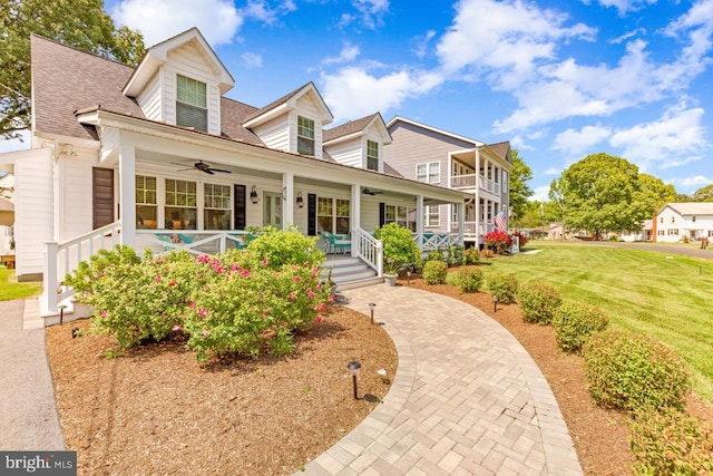 new england style home with a front yard, ceiling fan, and a porch