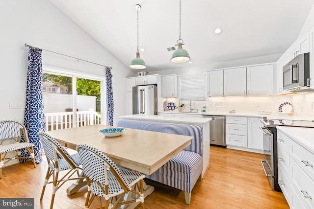 dining room featuring breakfast area, lofted ceiling, sink, and light hardwood / wood-style flooring