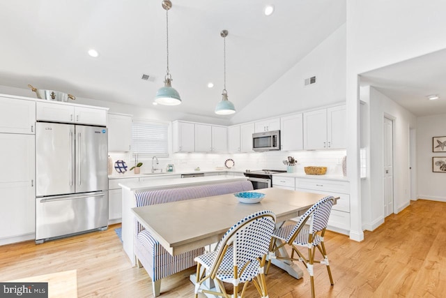 kitchen with pendant lighting, stainless steel appliances, white cabinets, and a kitchen island