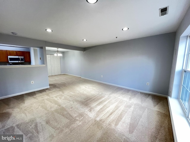 carpeted empty room featuring a notable chandelier