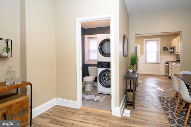 washroom with stacked washer and dryer and light wood-type flooring