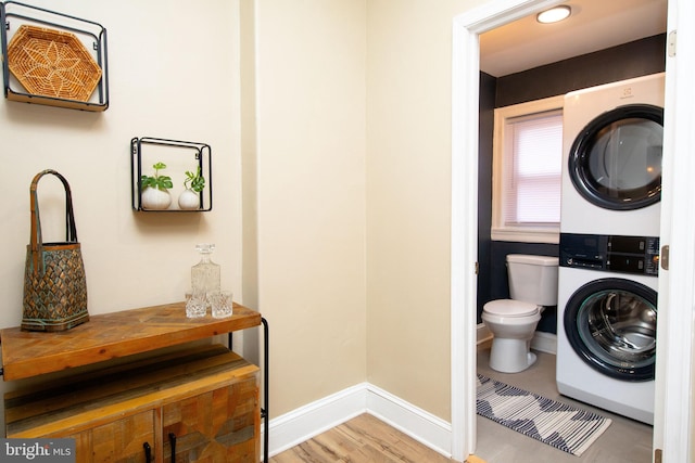 washroom featuring hardwood / wood-style flooring and stacked washer and clothes dryer