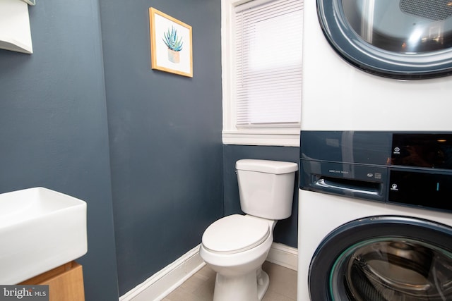 bathroom with toilet and stacked washer / dryer