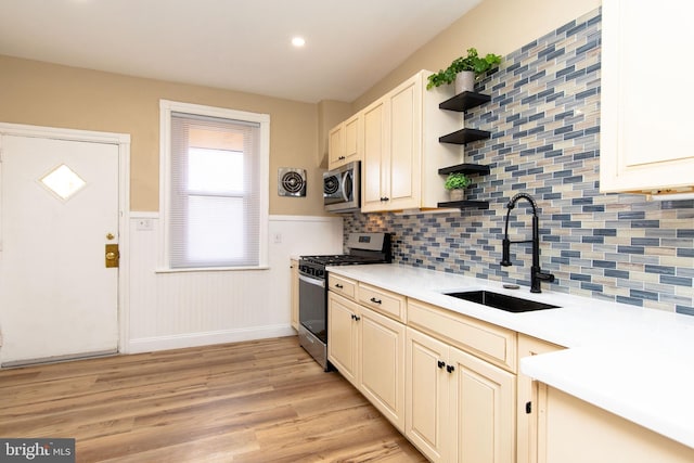 kitchen featuring tasteful backsplash, sink, stainless steel appliances, and light hardwood / wood-style floors