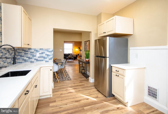 kitchen featuring stainless steel refrigerator, sink, light hardwood / wood-style flooring, and backsplash