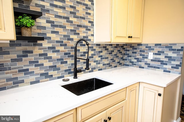 kitchen with cream cabinets, sink, and decorative backsplash