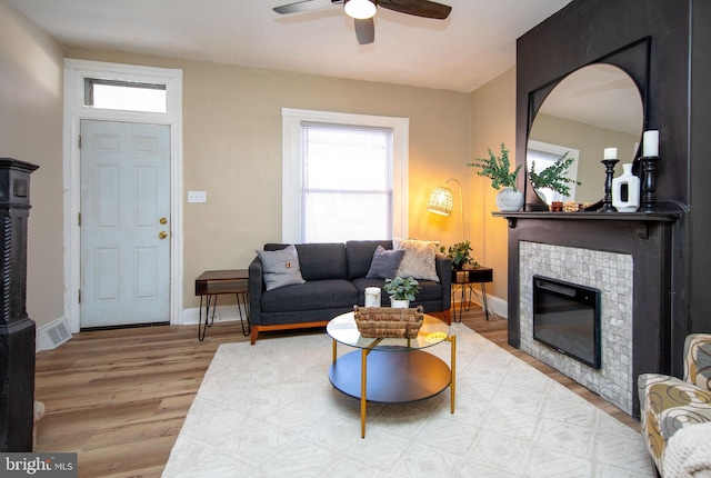 living room with hardwood / wood-style flooring, ceiling fan, and a fireplace