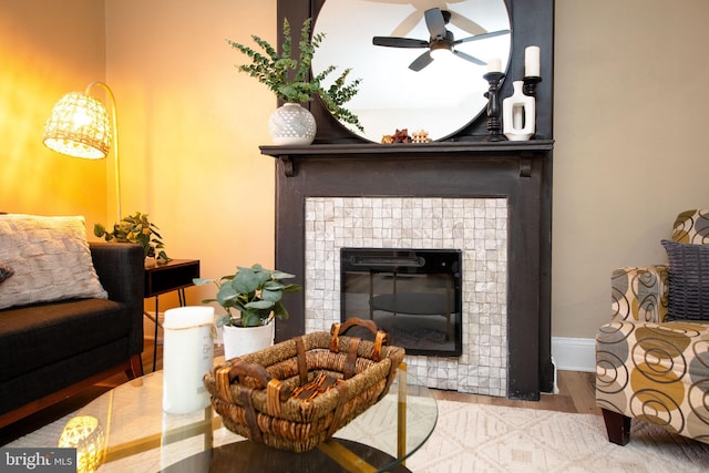 interior space with a tiled fireplace, hardwood / wood-style flooring, and ceiling fan