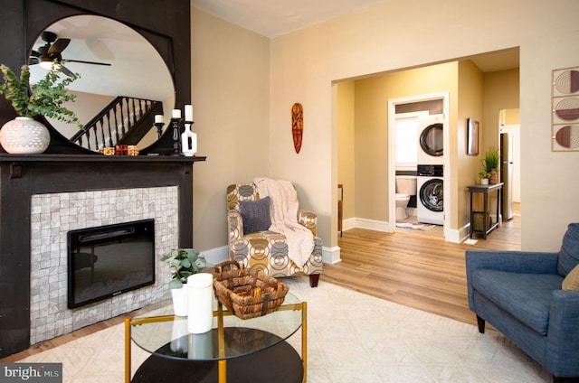 living room with stacked washer / dryer, ceiling fan, a fireplace, and light hardwood / wood-style floors