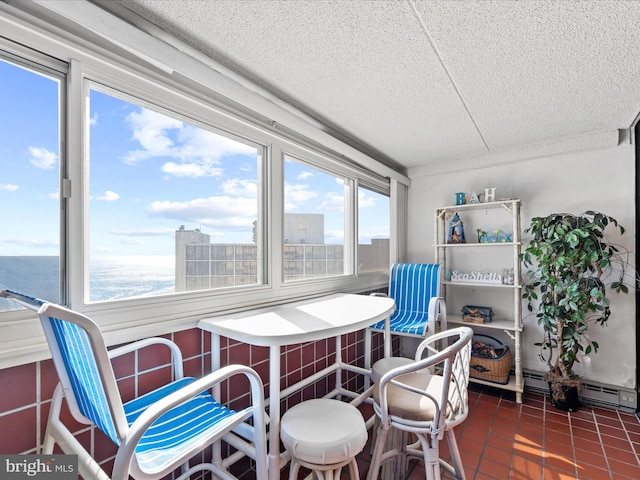 dining room featuring dark tile patterned flooring, a baseboard radiator, a textured ceiling, and a water view