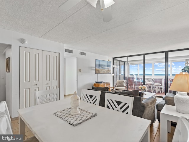 dining area featuring expansive windows, ceiling fan, and a textured ceiling