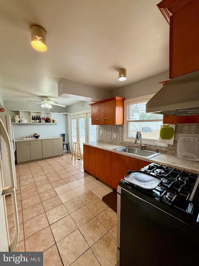 kitchen featuring light tile patterned flooring, range with gas stovetop, sink, island exhaust hood, and white fridge