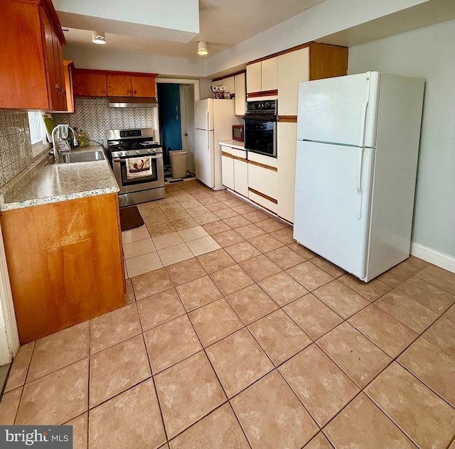 kitchen featuring sink, black oven, gas stove, and white refrigerator