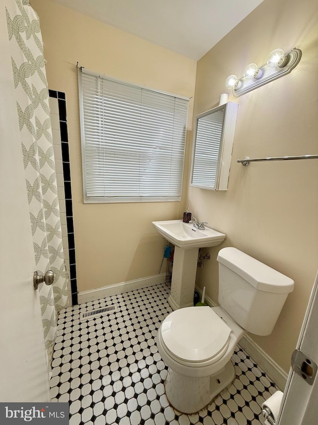 bathroom featuring sink, curtained shower, and toilet