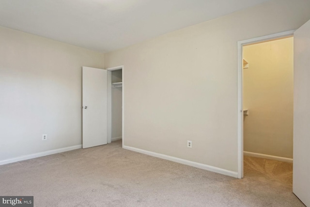 unfurnished bedroom featuring light colored carpet, a spacious closet, and a closet