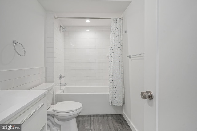 full bathroom with shower / bathtub combination with curtain, tile walls, vanity, wood-type flooring, and toilet