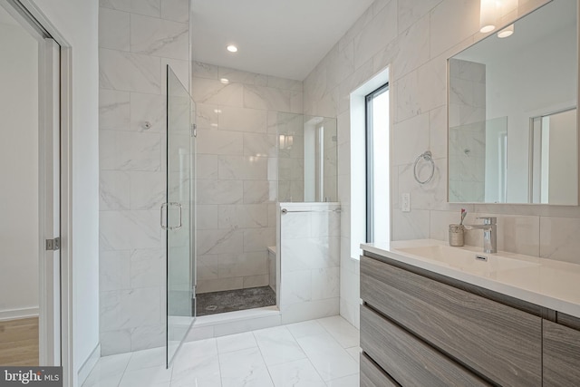 bathroom with a shower with door, vanity, and tile walls