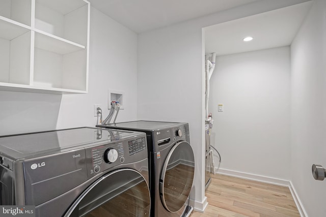 laundry area featuring washer and clothes dryer and light hardwood / wood-style floors