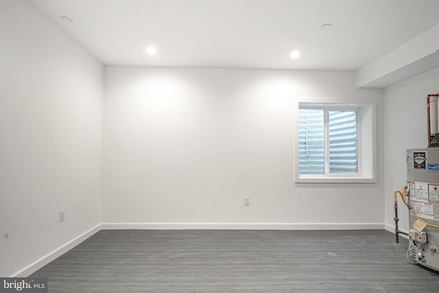 empty room featuring dark wood-type flooring and water heater