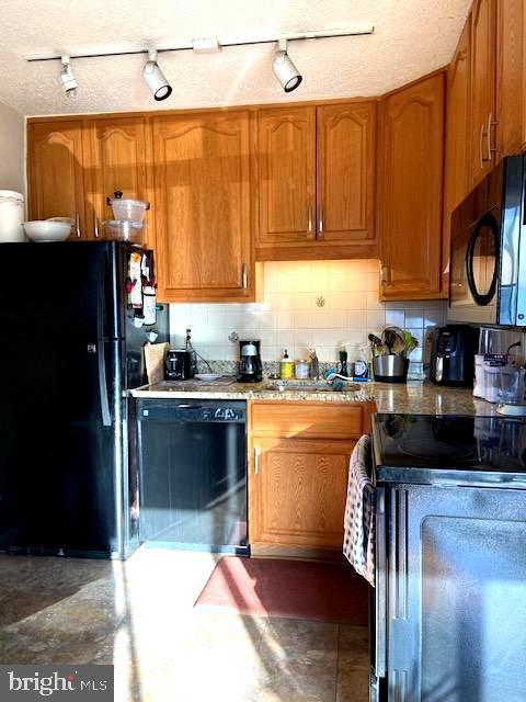 kitchen featuring sink, tasteful backsplash, a textured ceiling, and black appliances