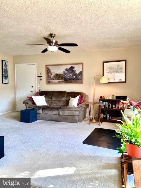 living room featuring a textured ceiling, carpet flooring, and ceiling fan