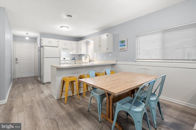 dining space with sink and light wood-type flooring