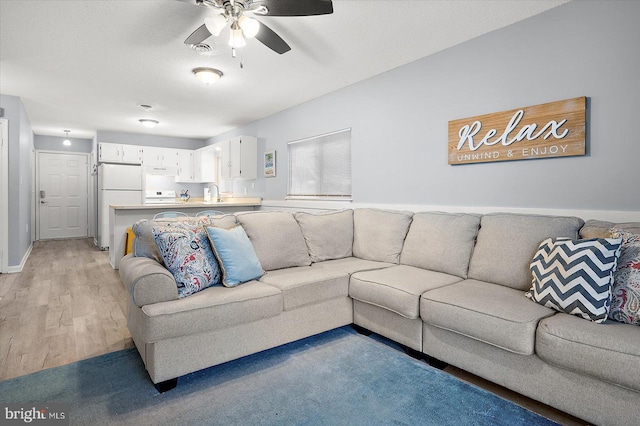 living room with sink, ceiling fan, and light hardwood / wood-style flooring