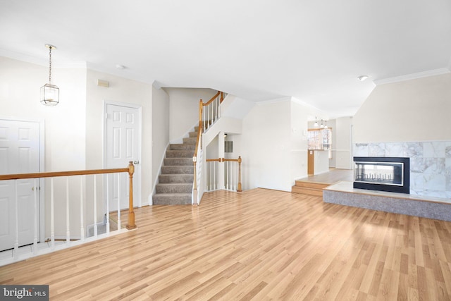 unfurnished living room featuring a premium fireplace, crown molding, and light hardwood / wood-style floors