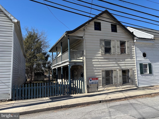 view of front of property featuring a fenced front yard and a balcony