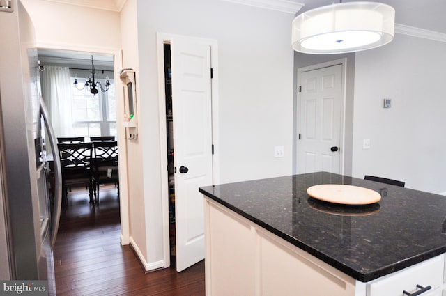 kitchen featuring stainless steel refrigerator with ice dispenser, white cabinetry, decorative light fixtures, ornamental molding, and dark stone counters