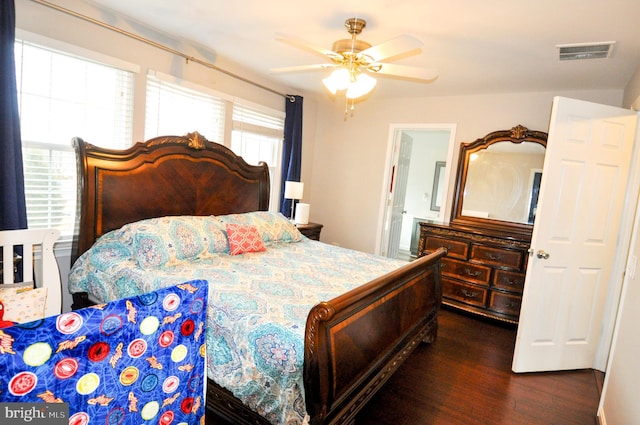 bedroom featuring multiple windows, dark wood-type flooring, connected bathroom, and ceiling fan