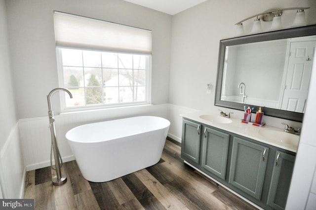 bathroom with wood-type flooring, a bath, and vanity