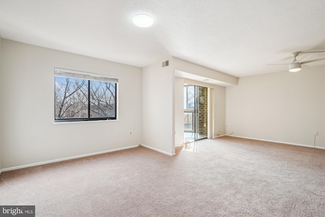 empty room featuring ceiling fan, light carpet, and a textured ceiling