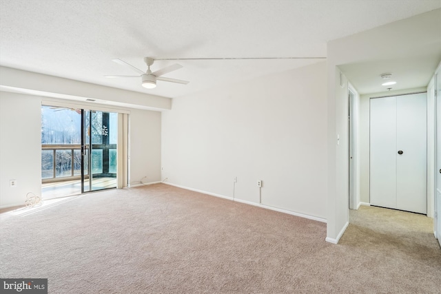 empty room with ceiling fan, light colored carpet, and a textured ceiling