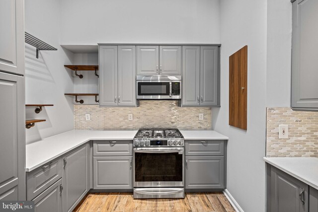 kitchen with appliances with stainless steel finishes, gray cabinetry, and decorative backsplash