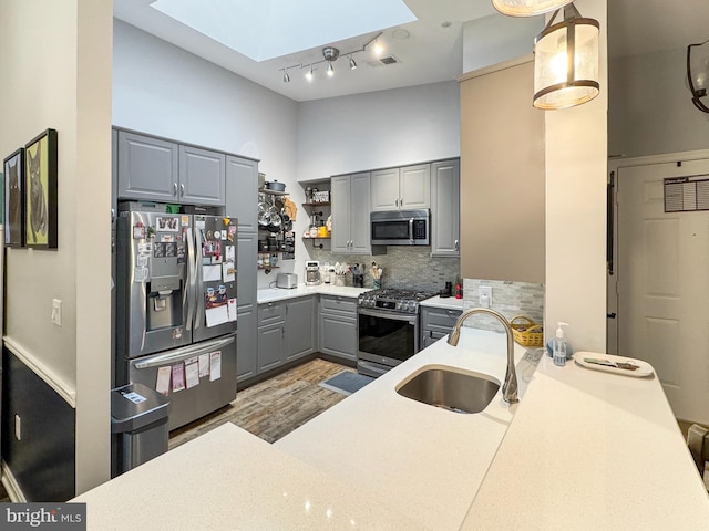 kitchen with sink, gray cabinets, a skylight, stainless steel appliances, and hanging light fixtures