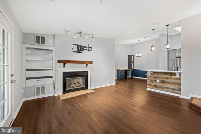 unfurnished living room with lofted ceiling, dark wood-type flooring, and built in shelves