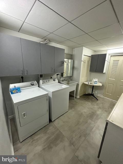 clothes washing area featuring cabinets, washer and clothes dryer, and sink