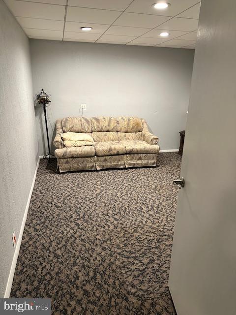 carpeted living room featuring a paneled ceiling