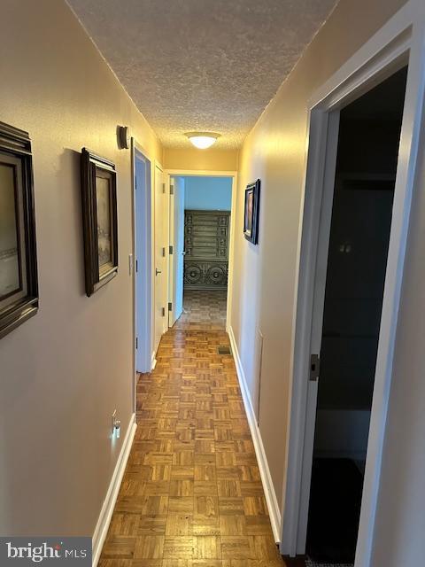 corridor featuring light parquet flooring and a textured ceiling